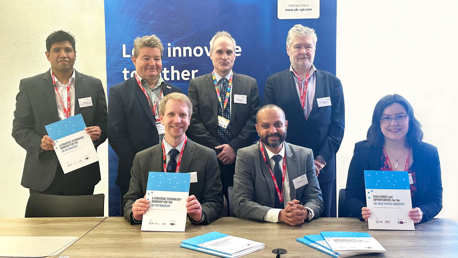 A group of people from CPI, ABHI, CDP and Innovate UK are either stood up or sat down at a table in front of a blue CPI 'Let's Innovate Together' Banner. Some are holding up hard copies of the HealthTech Industry insights reports. A group of people from CPI, ABHI, CDP and Innovate UK are either stood up or sat down at a table in front of a blue CPI 'Let's Innovate Together' Banner. Some are holding up hard copies of the HealthTech Industry insights reports.