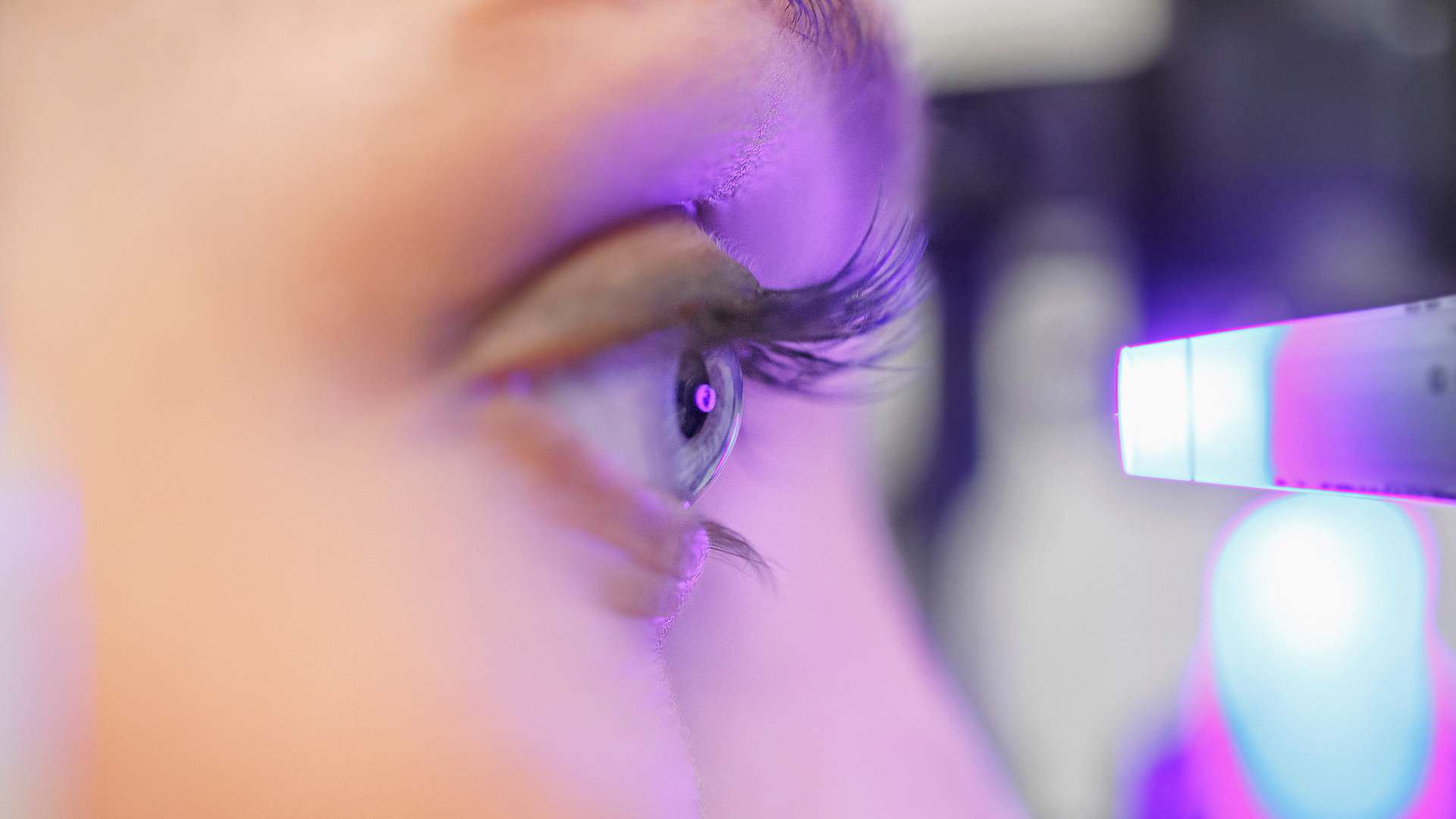 A photo of a person undergoing an eye examination with purple light A photo of a person undergoing an eye examination with purple light