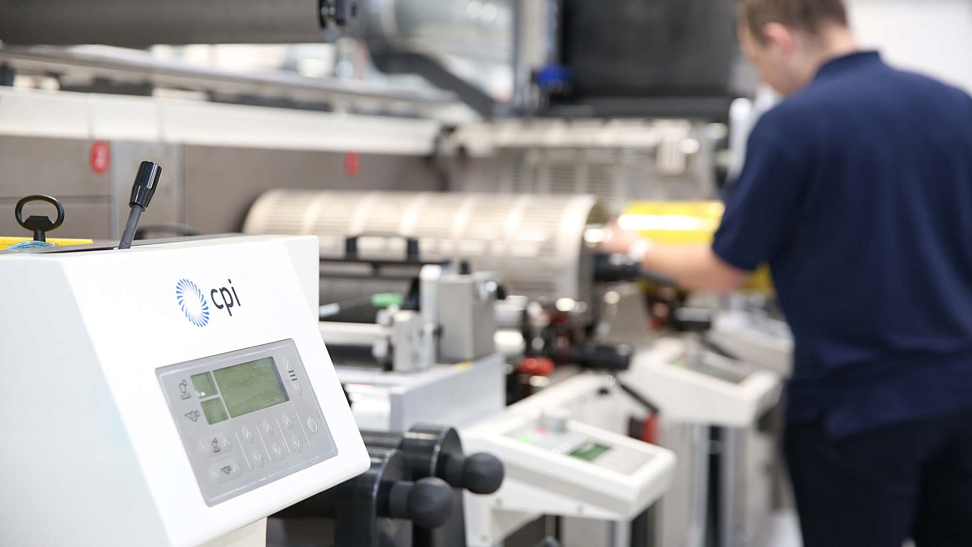 A photo of a CPI staff member working on a roll-to-roll printer A photo of a CPI staff member working on a roll-to-roll printer